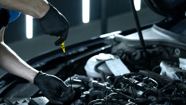 Photographe professionnelle montrant un carrossier en uniforme bleu dans un atelier de carrosserie automobile spécialisé, inspectant et mesurant une portière endommagée d'une voiture à l'aide d'une jauge de profondeur ou d'un outillage de diagnostic de carrosserie. L'atelier doit montrer des équipements de réparation de carrosserie (cabines, établis, outils spécialisés) distinct d'un atelier mécanique traditionnel. L'accent doit être mis sur le professionnalisme et la précision du diagnostic de carrosserie.
